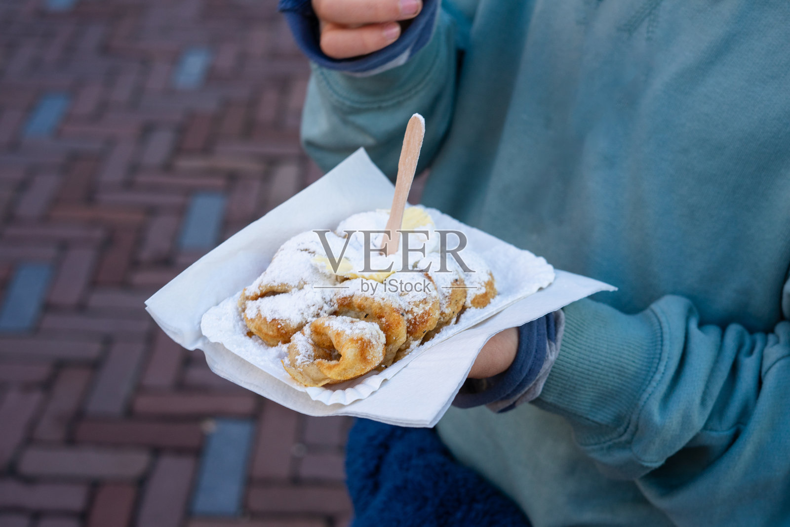 游客在阿姆斯特丹享用美味的荷兰小煎饼,撒上糖粉和黄油。照片摄影图片