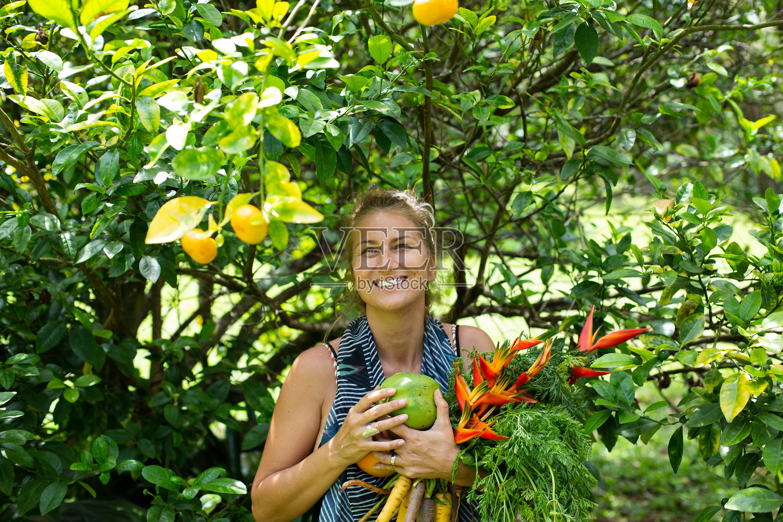 快乐健康的中年女性在夏威夷自然中微笑,手中捧着热带花卉和水果照片摄影图片