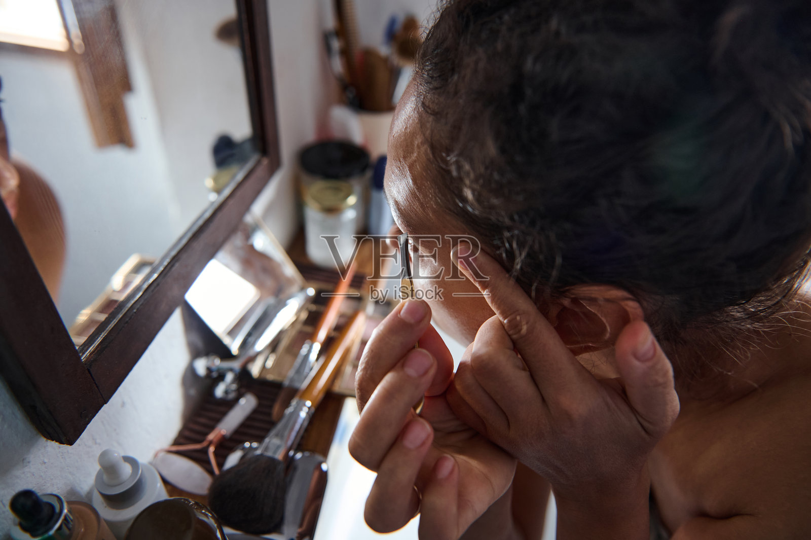 一个人在明亮的浴室里通过镜子检查自己的脸照片摄影图片