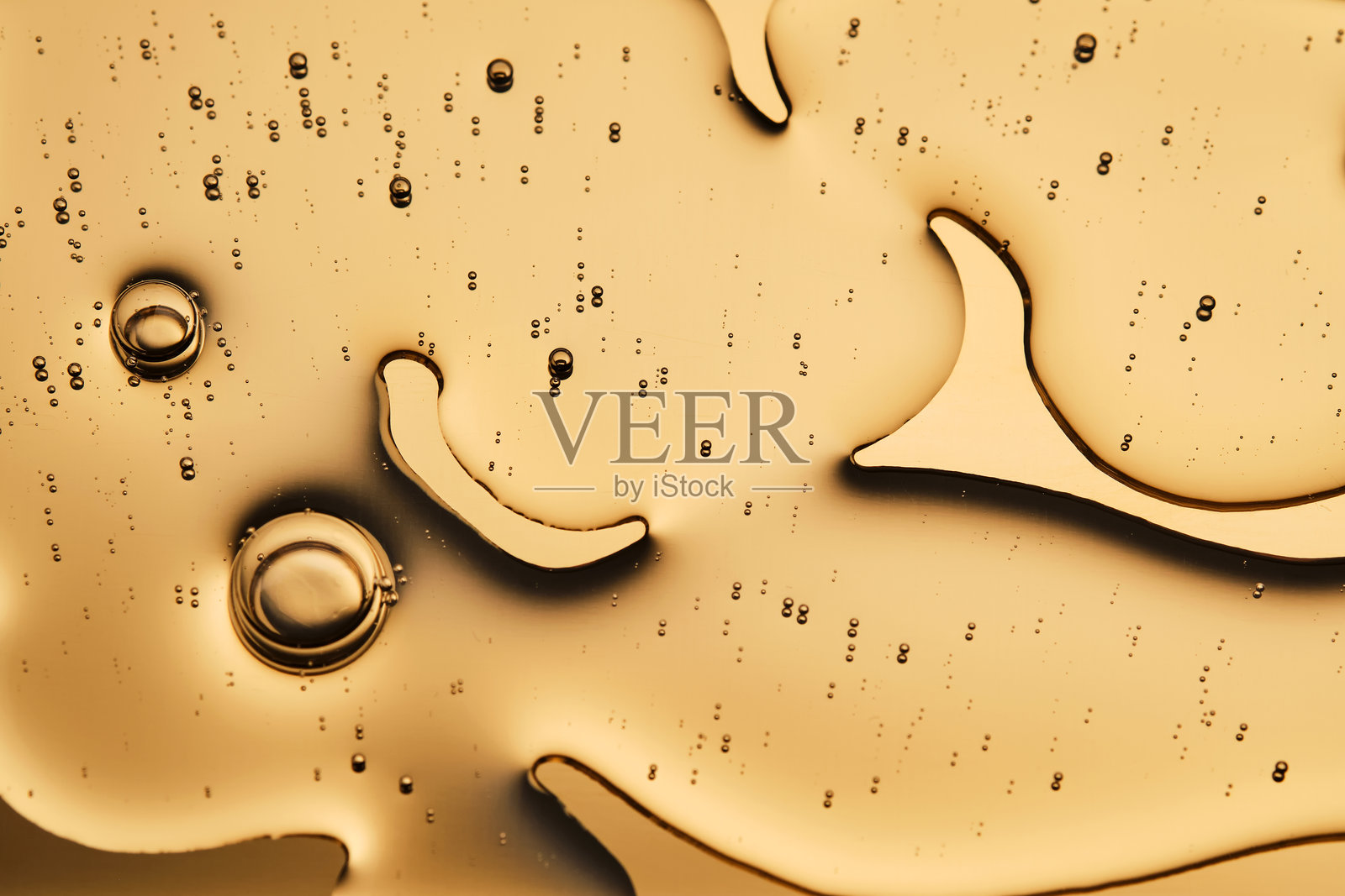 在金色背景上,化妆品精华的美丽质感占据了照片的大部分。照片摄影图片