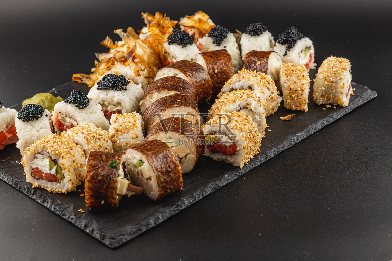 寿司拼盘,包含各种卷和配料,放在石板上。照片摄影图片
