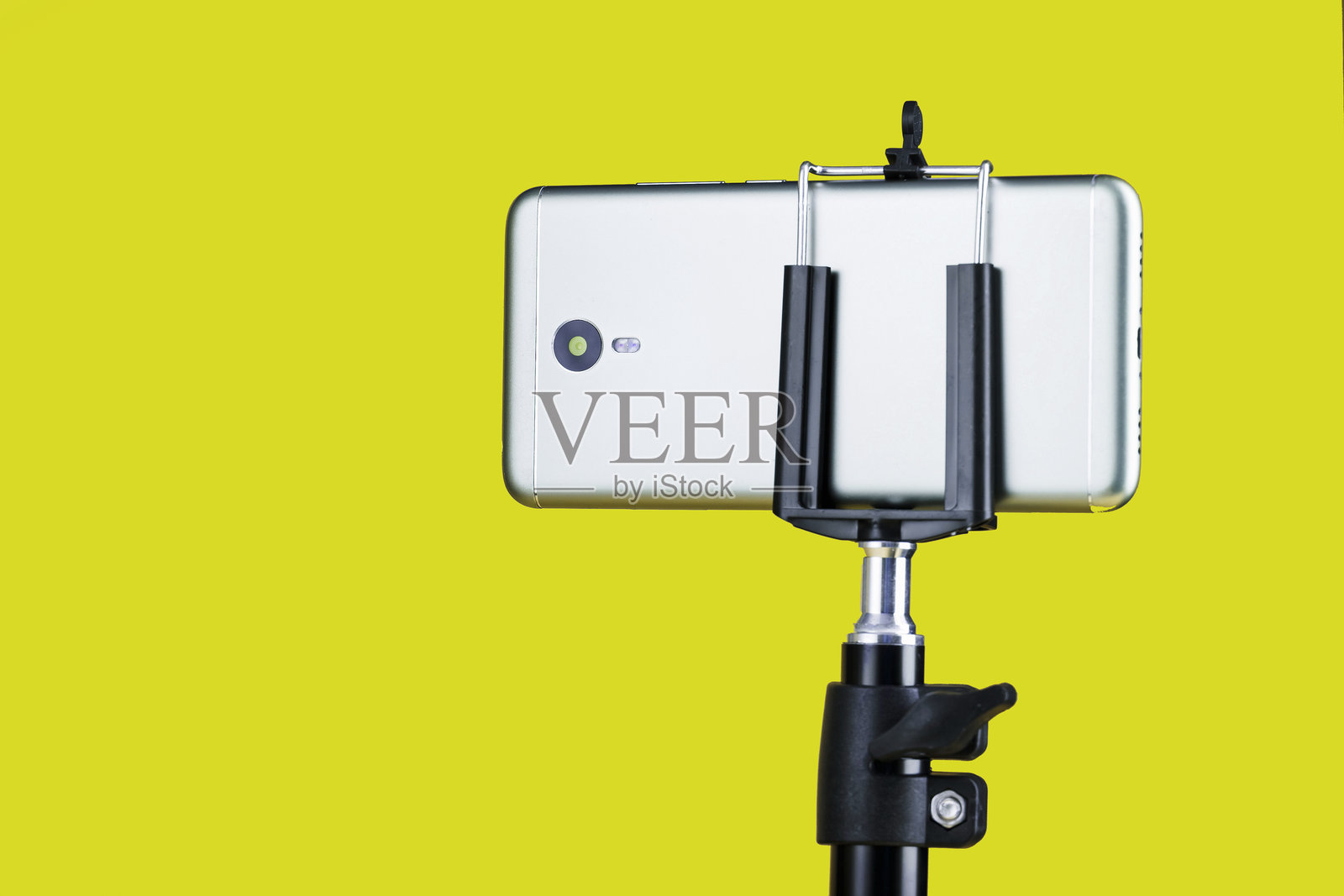 黄色背景上的三脚架上的智能手机,用于博客。照片摄影图片