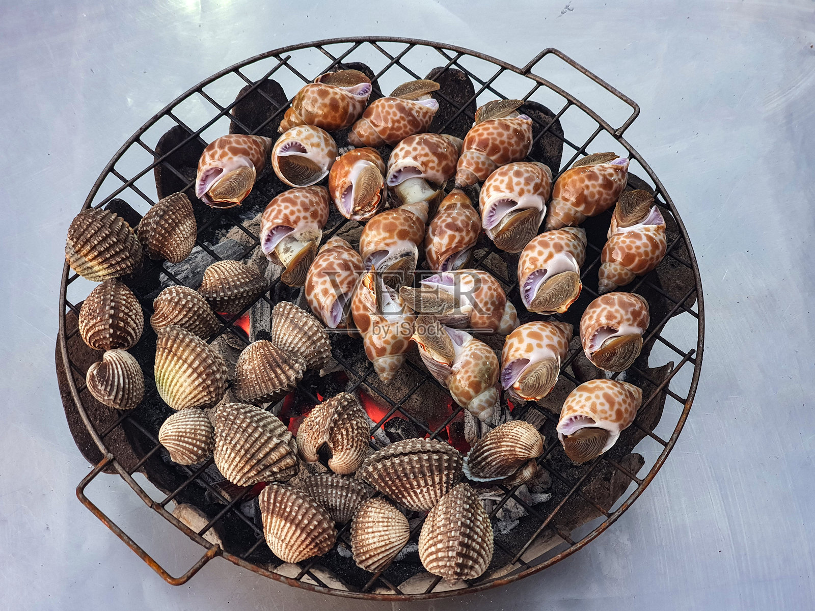 新鲜的蛤蜊在烤架上。用火烹饪。照片摄影图片