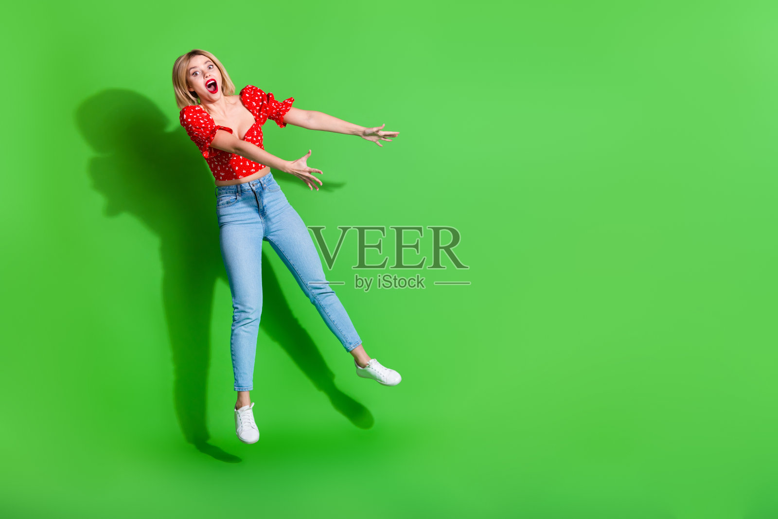惊讶女孩跳跃,吹气于空无一物的绿色背景上照片摄影图片