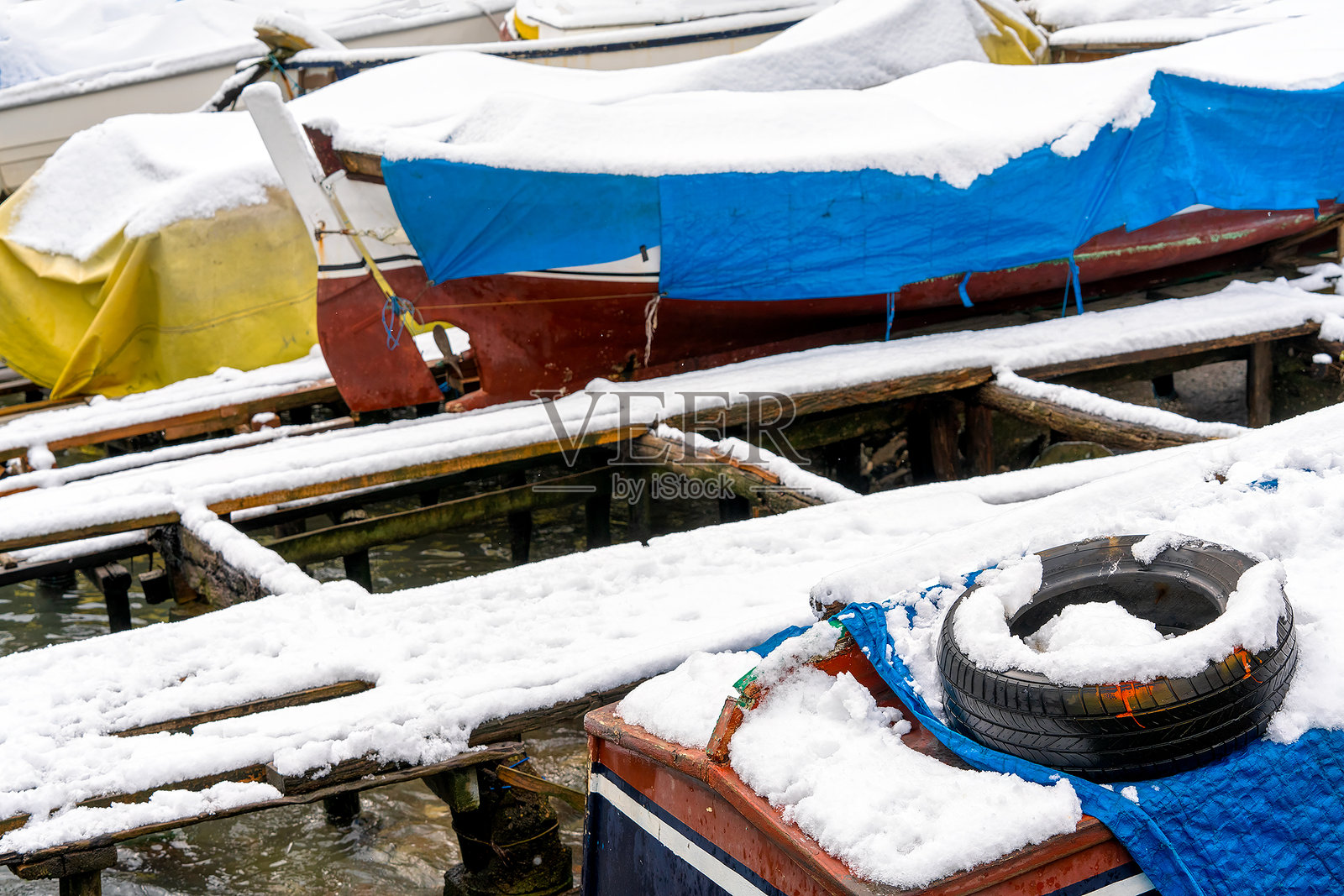 在博斯普鲁斯海峡的码头停靠着被雪覆盖的船只。照片摄影图片
