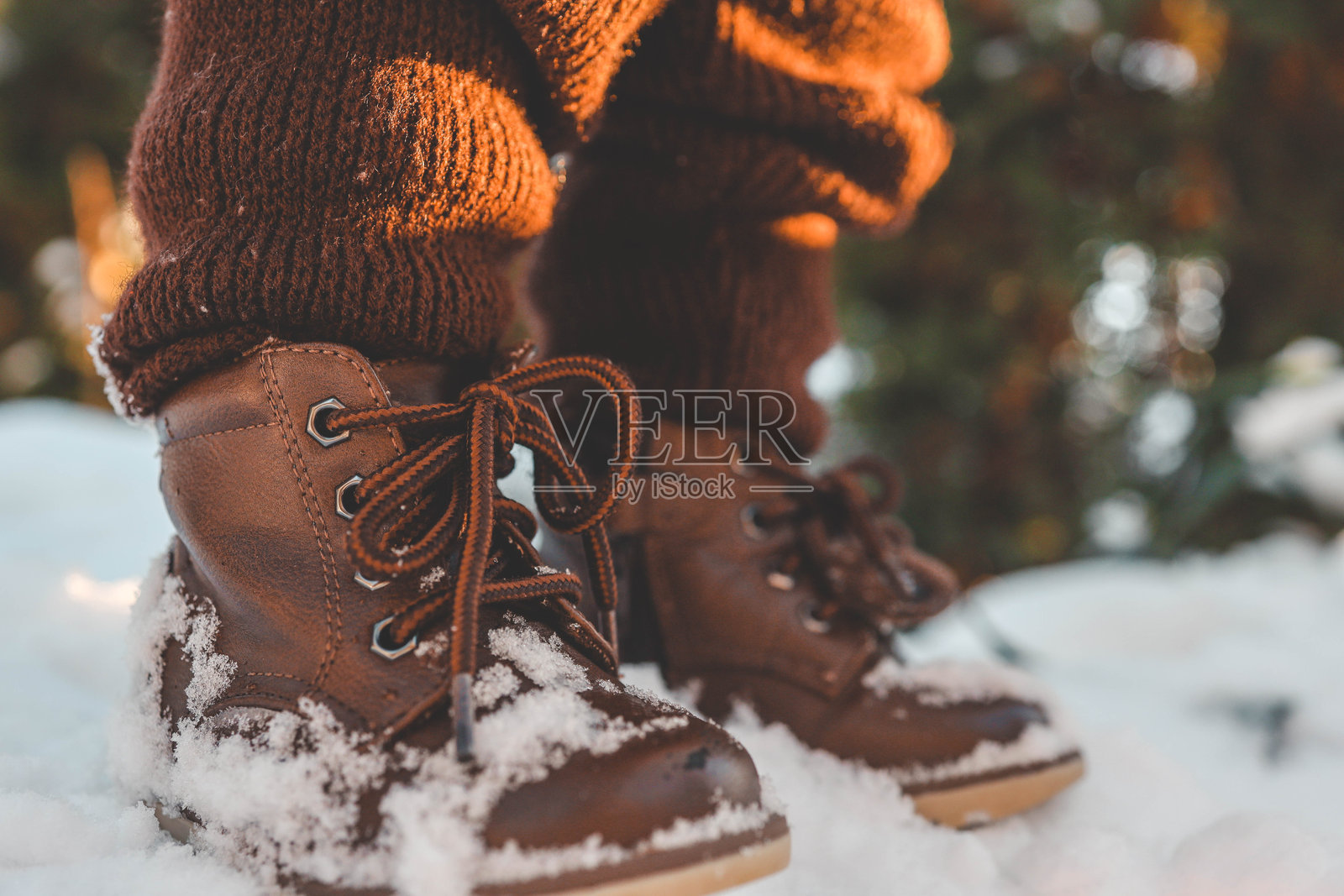 孩子在冬天的雪地里走路,特写镜头展示了脚上的靴子照片摄影图片