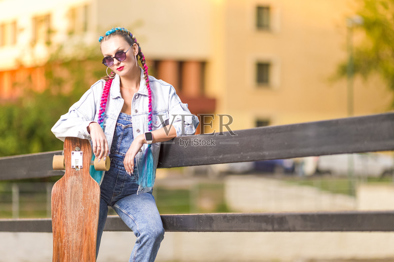 户外长板滑板的白人嬉皮女孩肖像,手持滑板。照片摄影图片