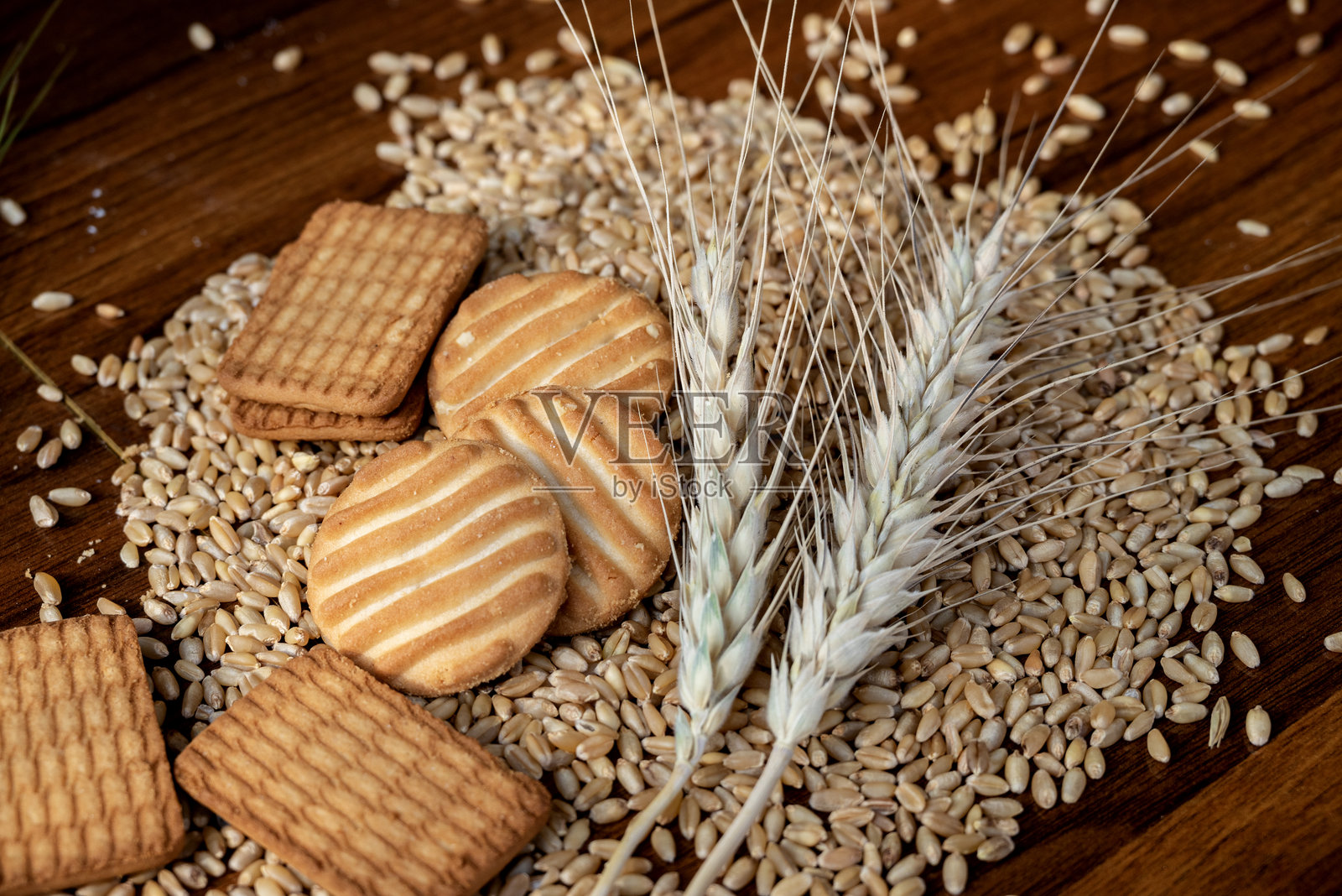 木桌背景上的饼干颗粒、小麦粉和麦穗特写照片摄影图片
