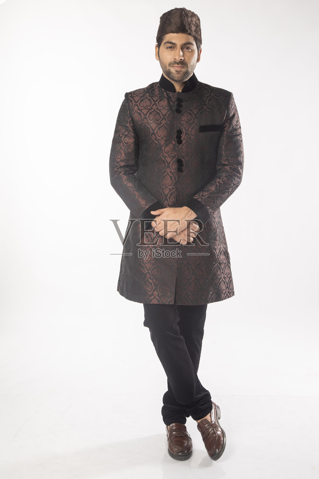 自信的新郎穿着黑色库尔塔,站在白色背景前照片摄影图片