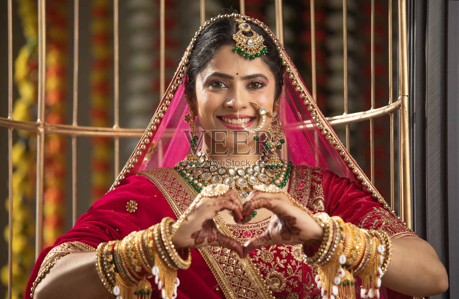 穿着红色婚纱的幸福新娘做出心形手势照片摄影图片