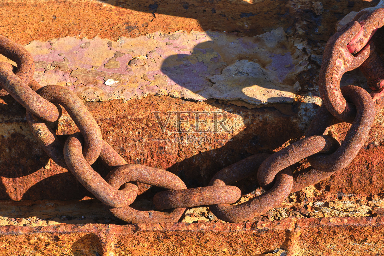 生锈的链条在风化的表面上投下阴影照片摄影图片