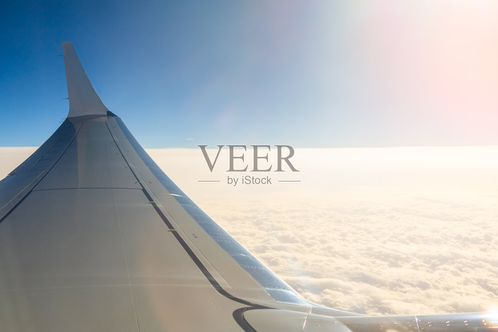 在阳光明媚的日子里,飞机的机翼高高伸展,穿越云层,延伸至湛蓝的天空。照片摄影图片