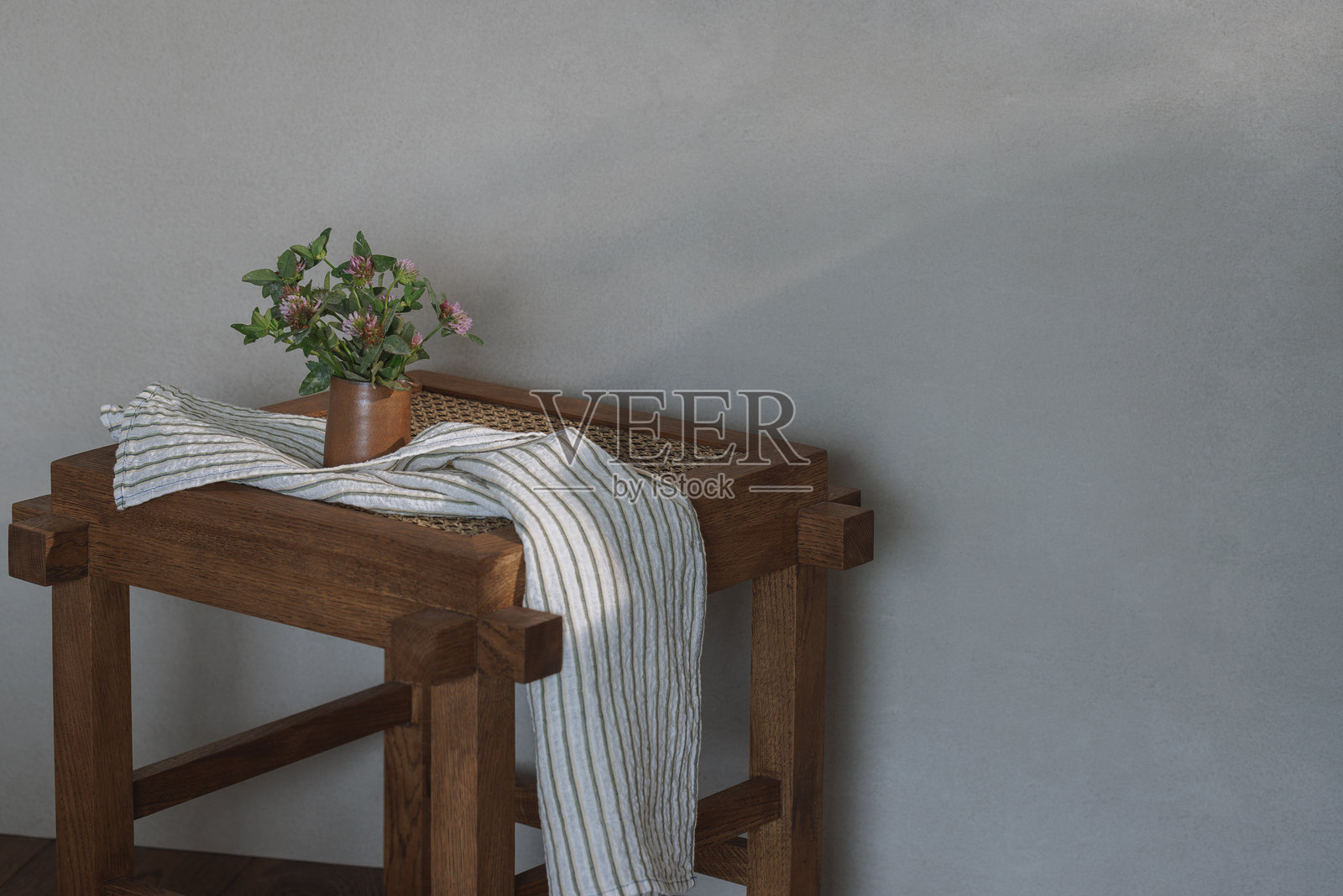 野生三叶草放在陶瓷壶中,置于藤椅上作为装饰元素。厨房美学概念照片摄影图片