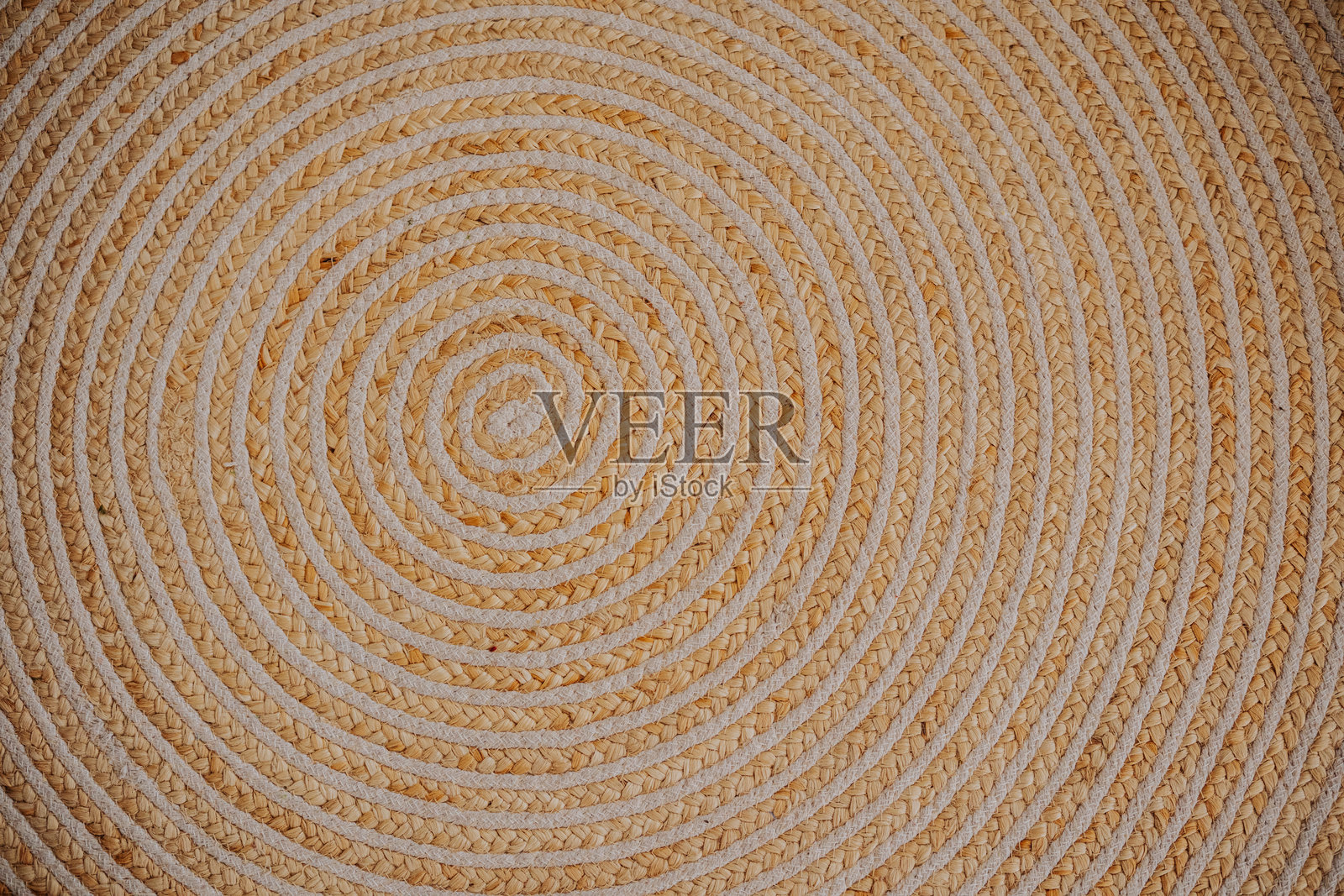 温暖色调中带有复杂螺旋图案的圆形编织垫子照片摄影图片