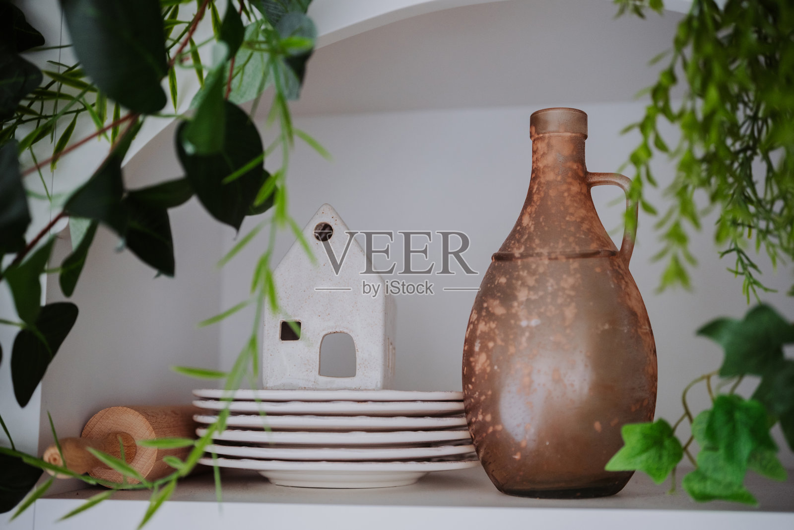 装饰性陶器和陶瓷房屋放在带有绿植的架子上照片摄影图片