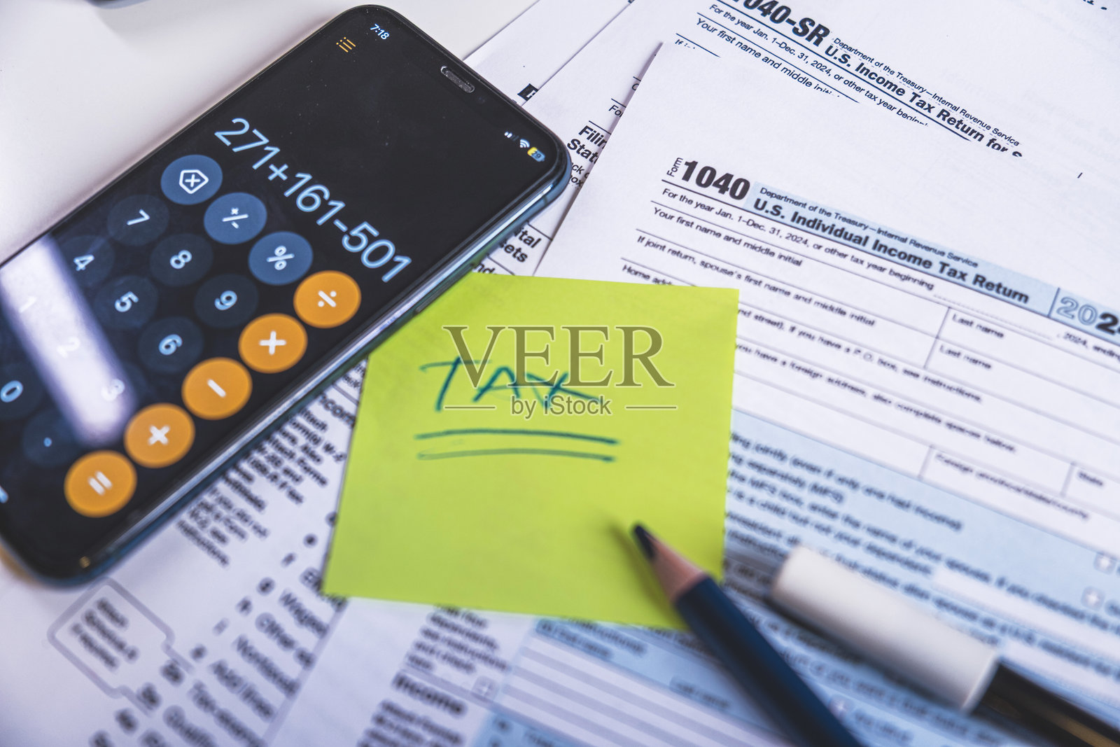 会计师使用智能手机上的计算器应用程序计算税款照片摄影图片