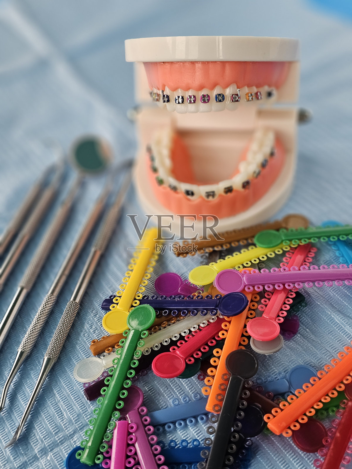 牙齿矫正器模型,配有彩色正畸橡皮圈和工具,放置在牙科治疗托盘上照片摄影图片