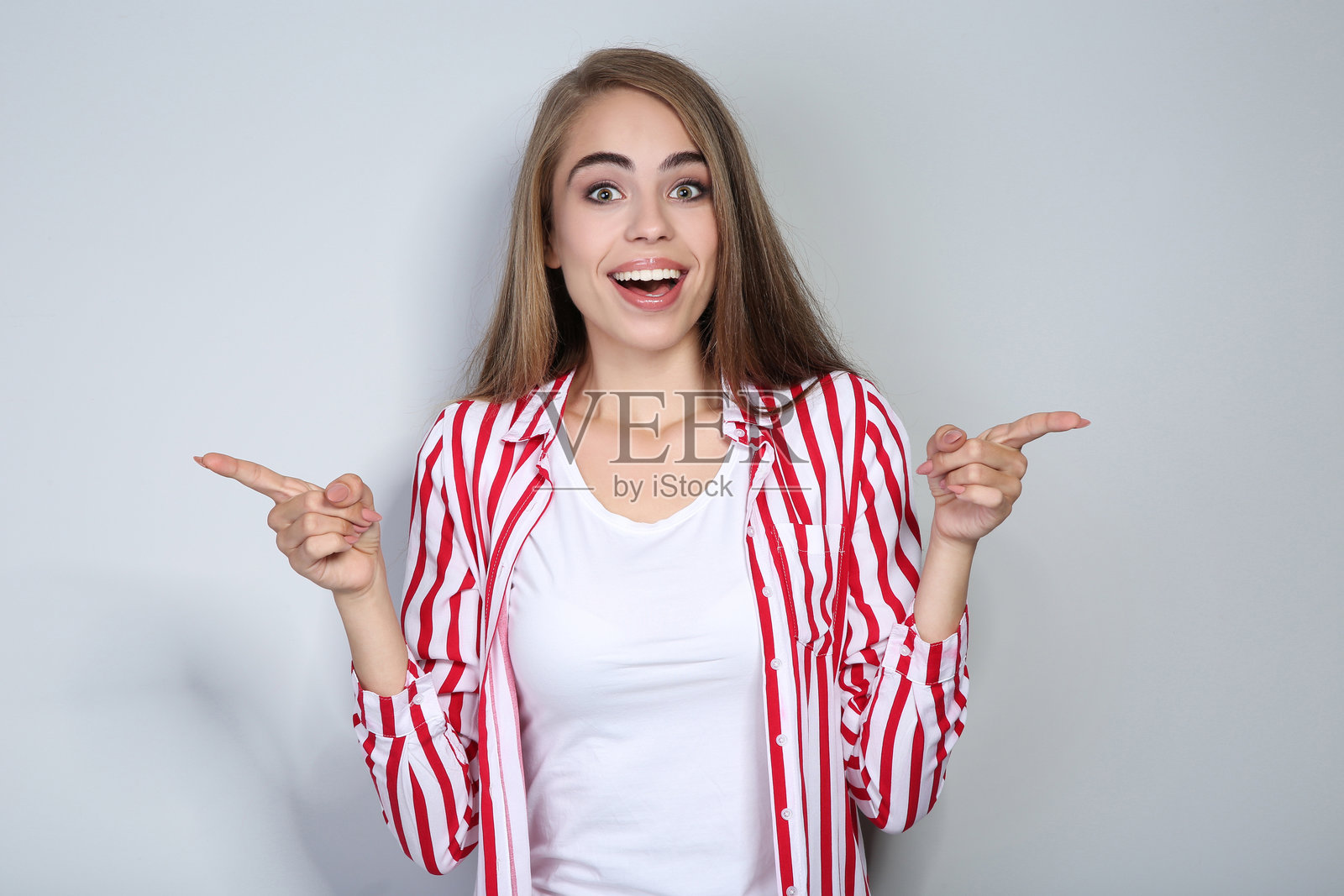 年轻漂亮的女孩在灰色背景上用手势表达。照片摄影图片