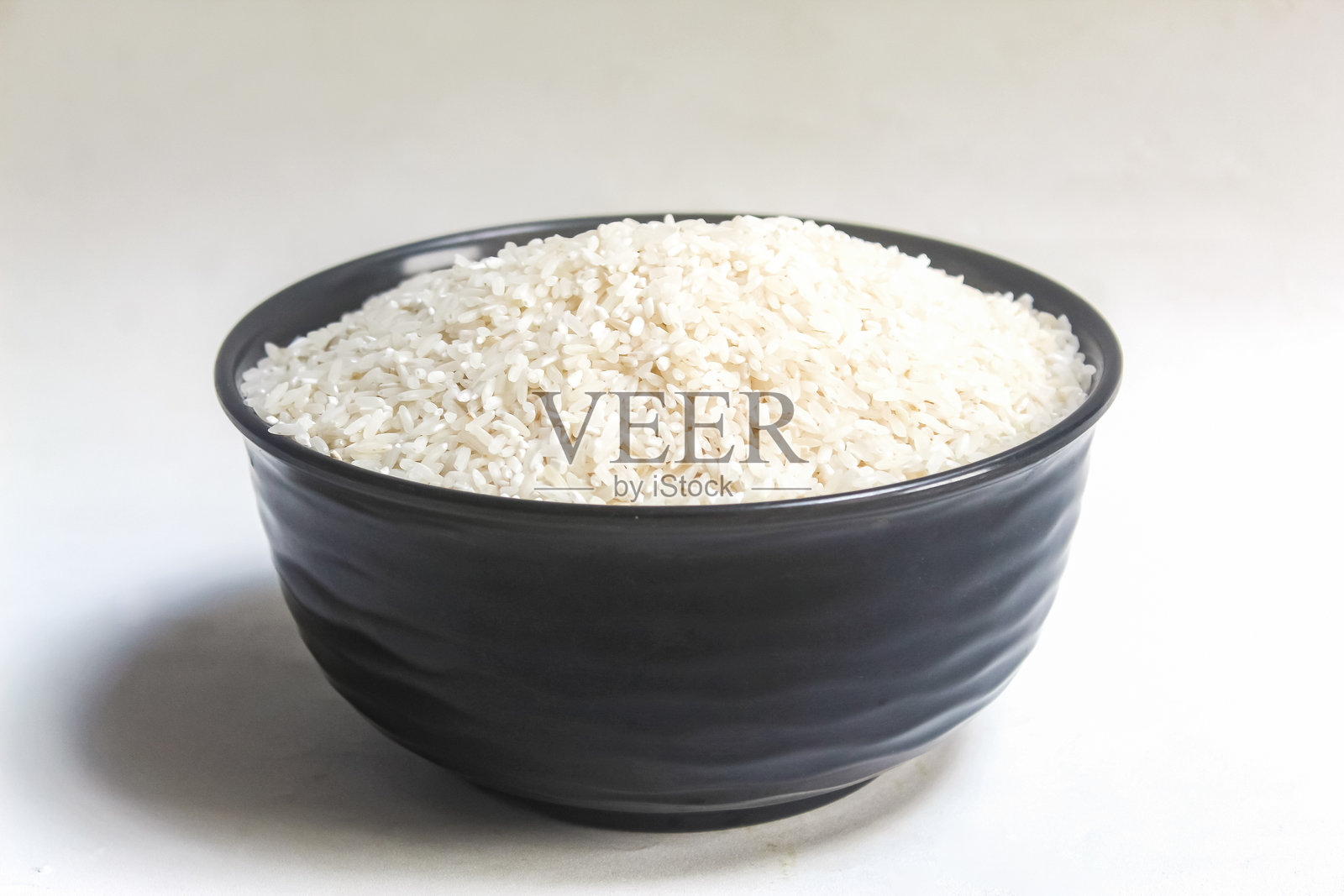 一碗生米放在白色背景上照片摄影图片
