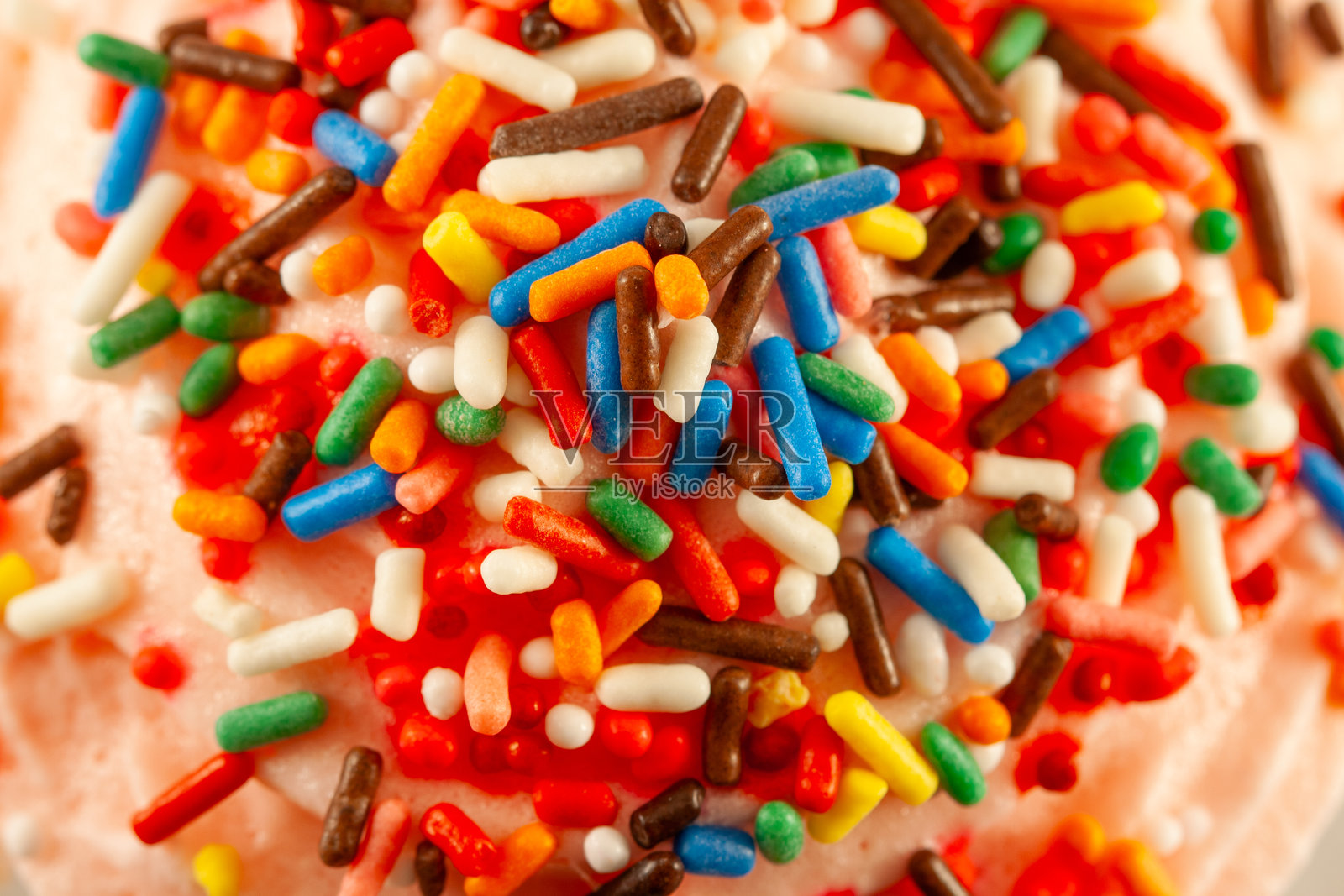 粉色糖霜与五彩糖屑背景的俯视特写图。照片摄影图片