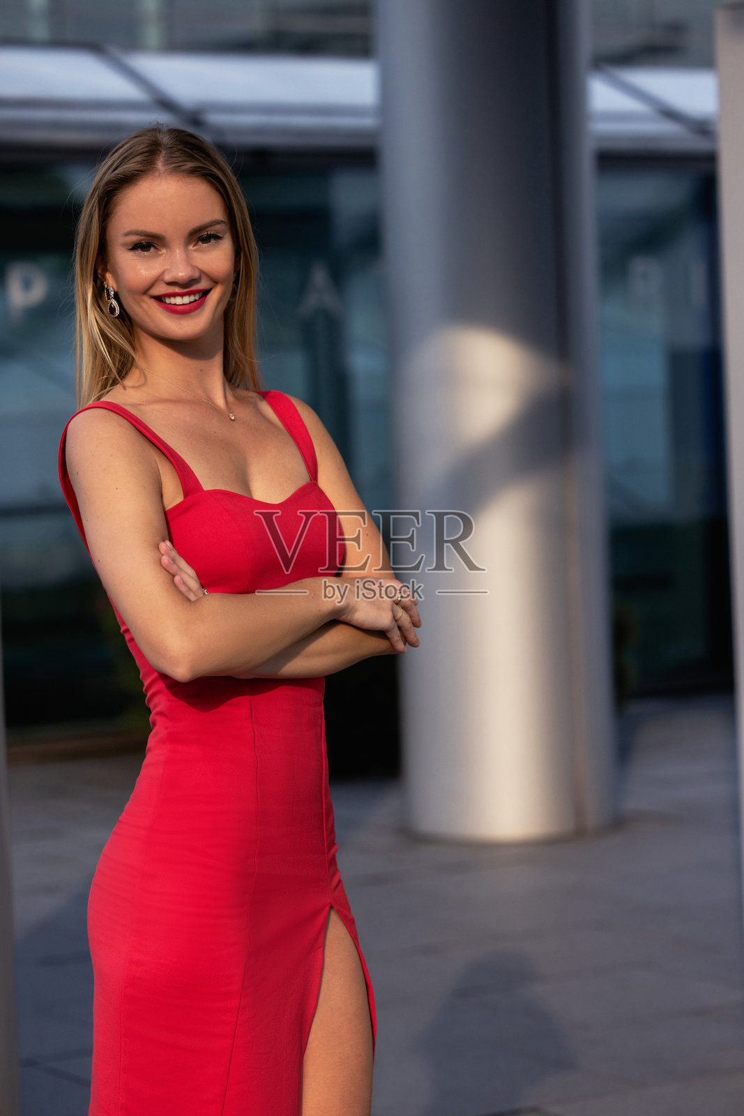 穿着红色连衣裙的美丽金发女孩,完美的腿部搭配丝袜和高跟鞋,摆姿势。照片摄影图片