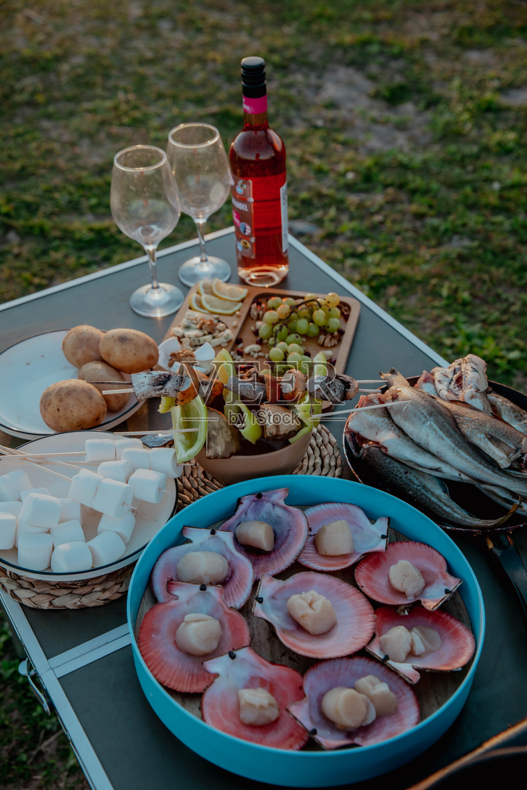 在大自然中享受野餐,配有葡萄酒、生蚝、海扇贝、奶酪拼盘和熏鱼照片摄影图片