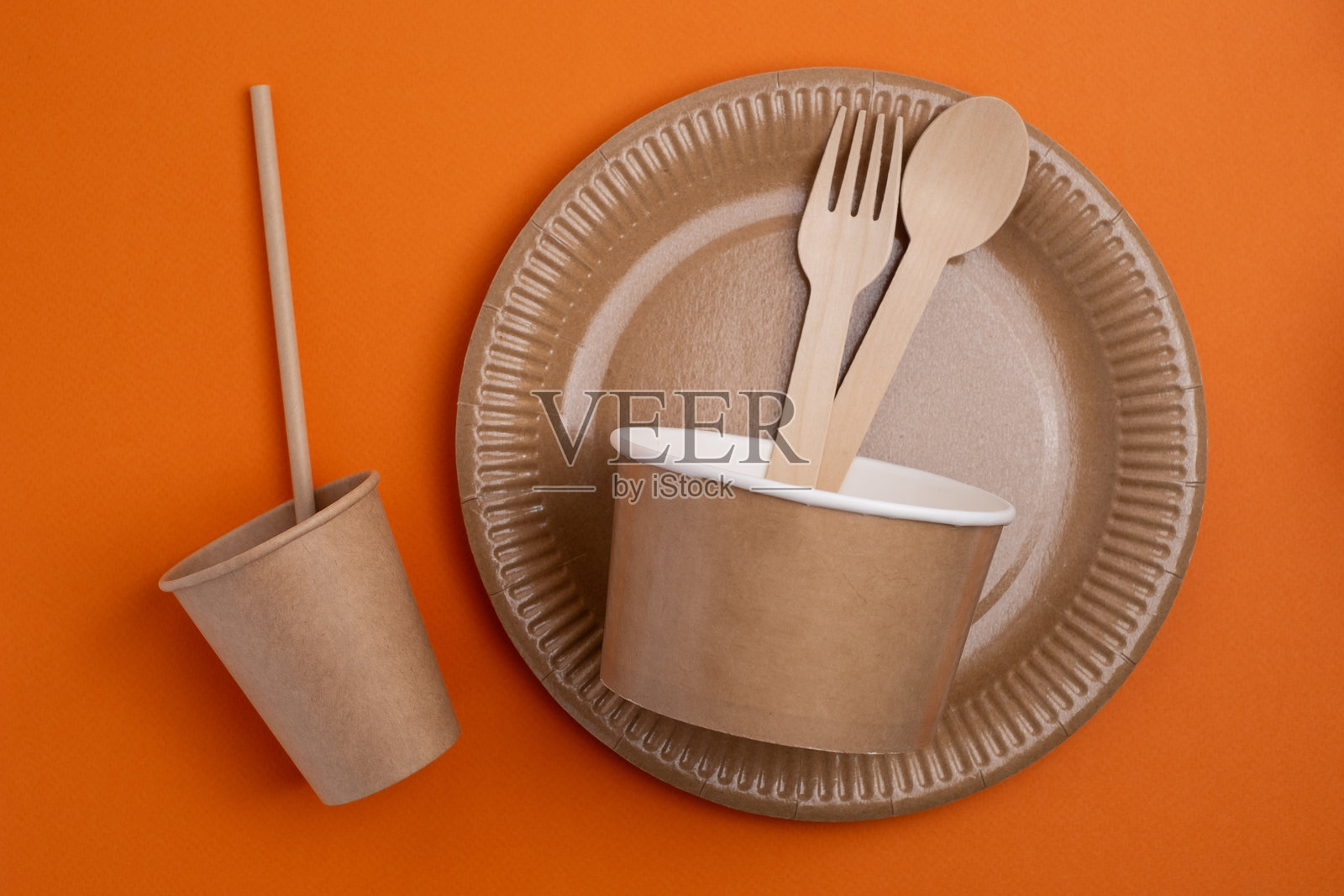 一堆环保一次性餐具。木制叉子和刀子,纸杯和纸盘在浅色背景上。适合野餐和外卖食品的可生物降解餐具和餐盘。照片摄影图片