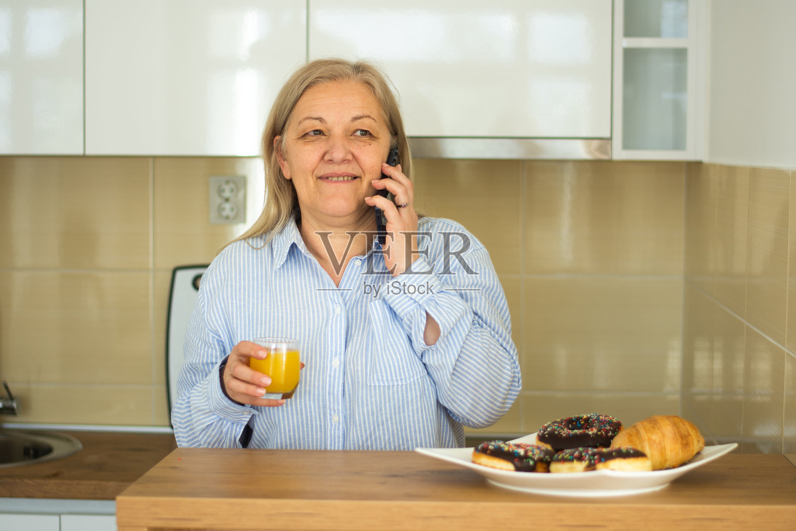 成熟的女性在厨房早餐时使用智能手机照片摄影图片