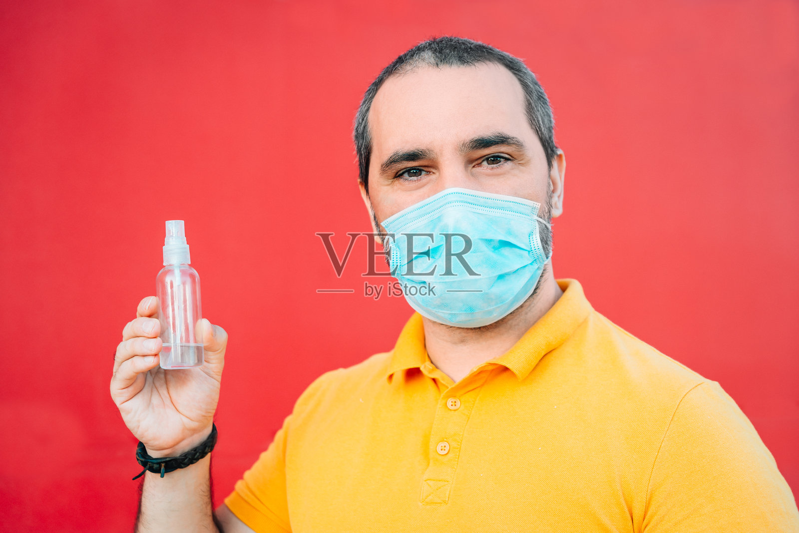 男子在红色背景下展示消毒液瓶子照片摄影图片
