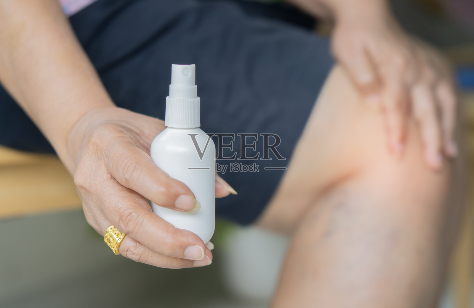 一位老年女性手持药瓶,背景模糊,显示出橘皮组织和静脉曲张。照片摄影图片