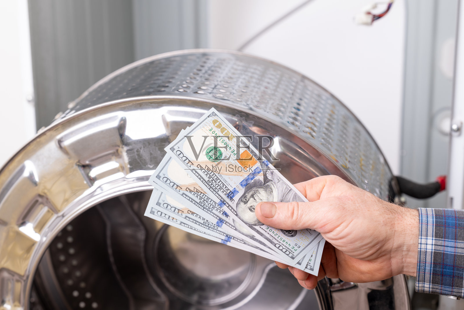 男子手握美元钞票,旁边是准备支付服务费用的洗衣机零件照片摄影图片