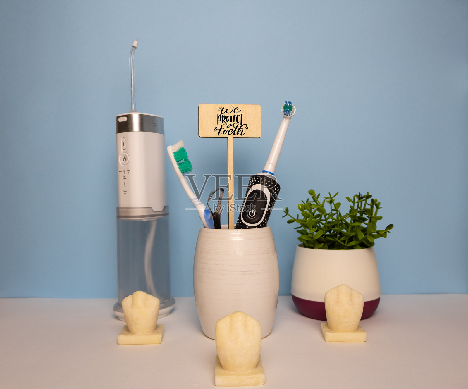 牙医背景,配有冲洗器、牙刷、装饰性牙齿植物和木制标牌“我们保护您的牙齿”照片摄影图片