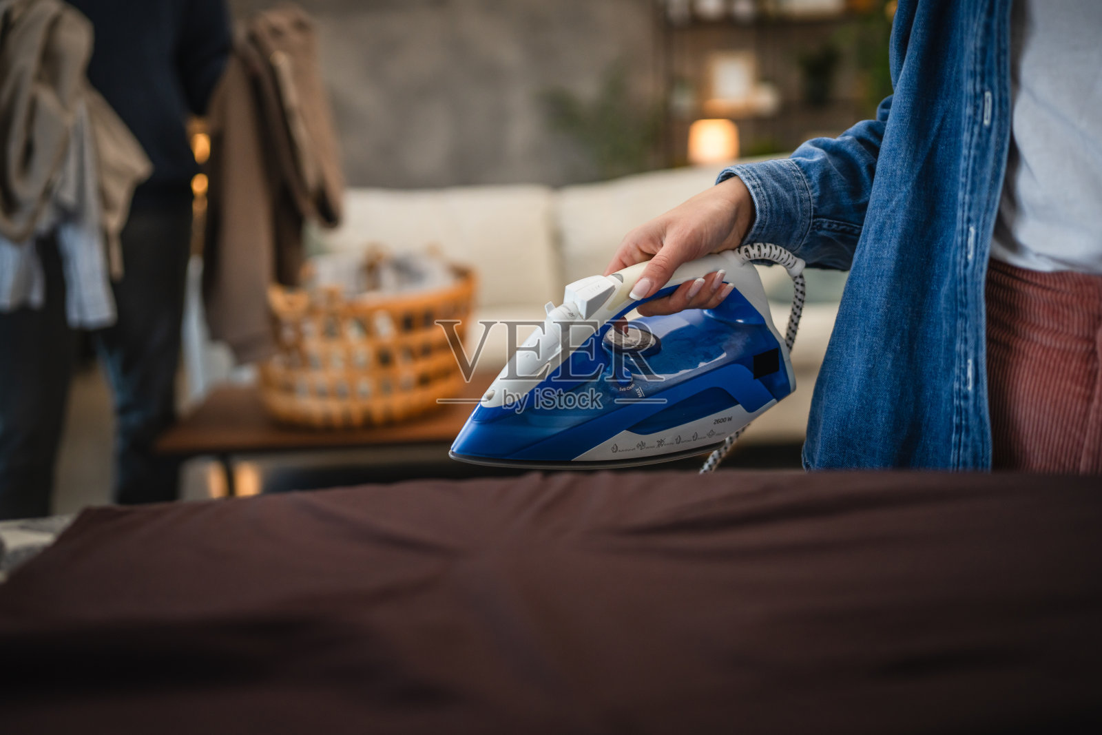 特写镜头下的女性在熨烫熨衣板上的棕色衬衫照片摄影图片