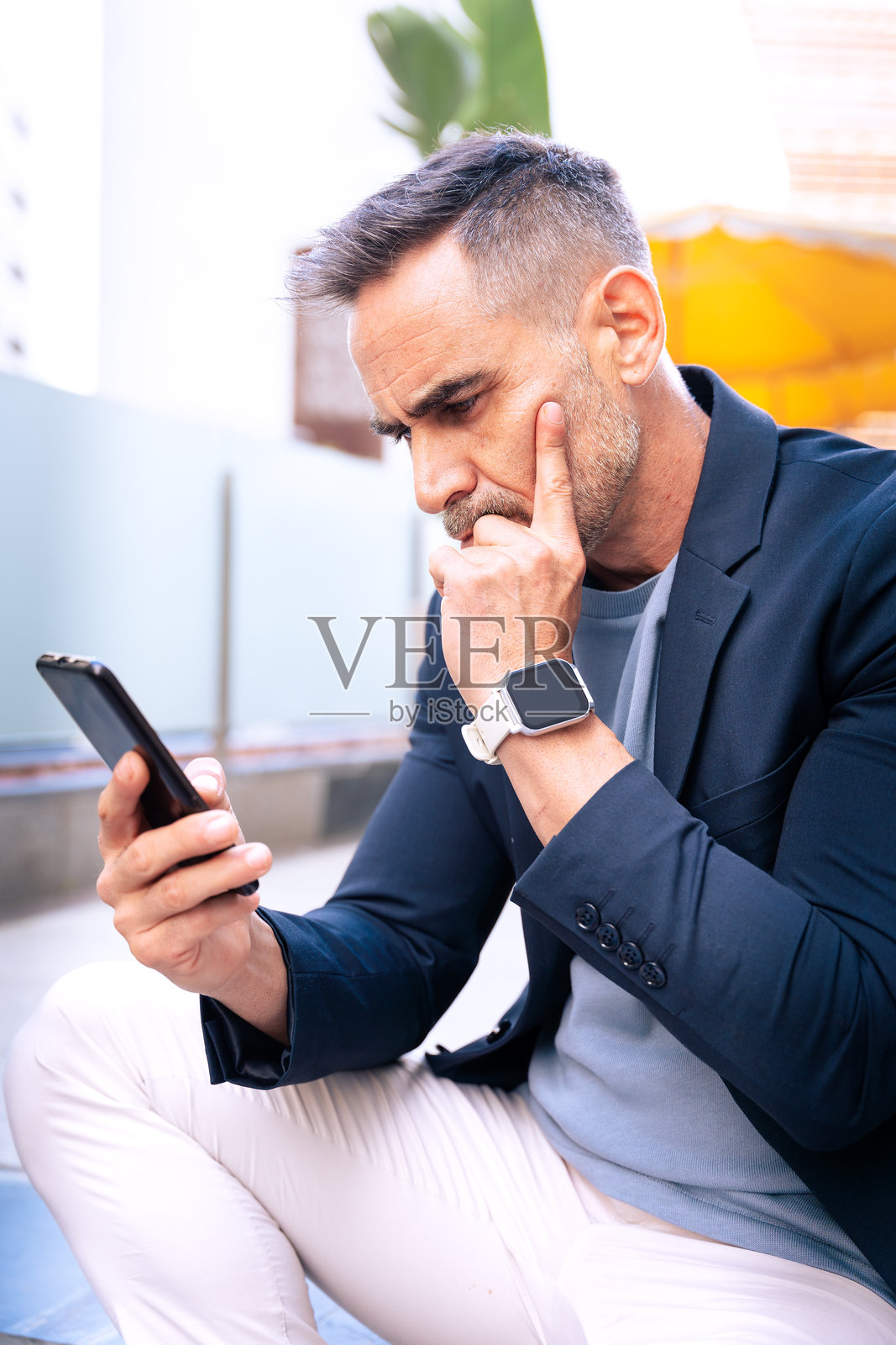 深思熟虑的商人在户外查看智能手机(竖版)照片摄影图片