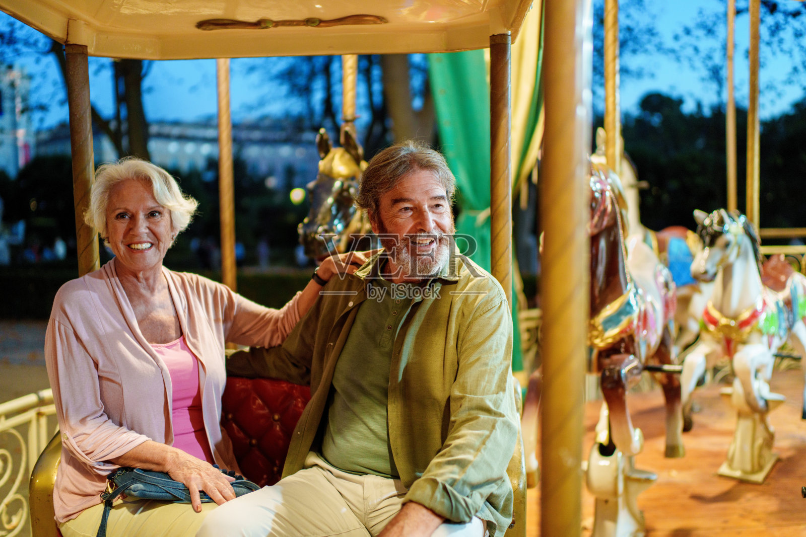 快乐的老年夫妇在游乐园享受旋转木马的乐趣照片摄影图片