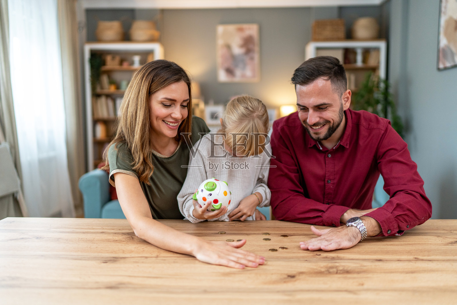 一家人一起往储蓄罐里投硬币照片摄影图片