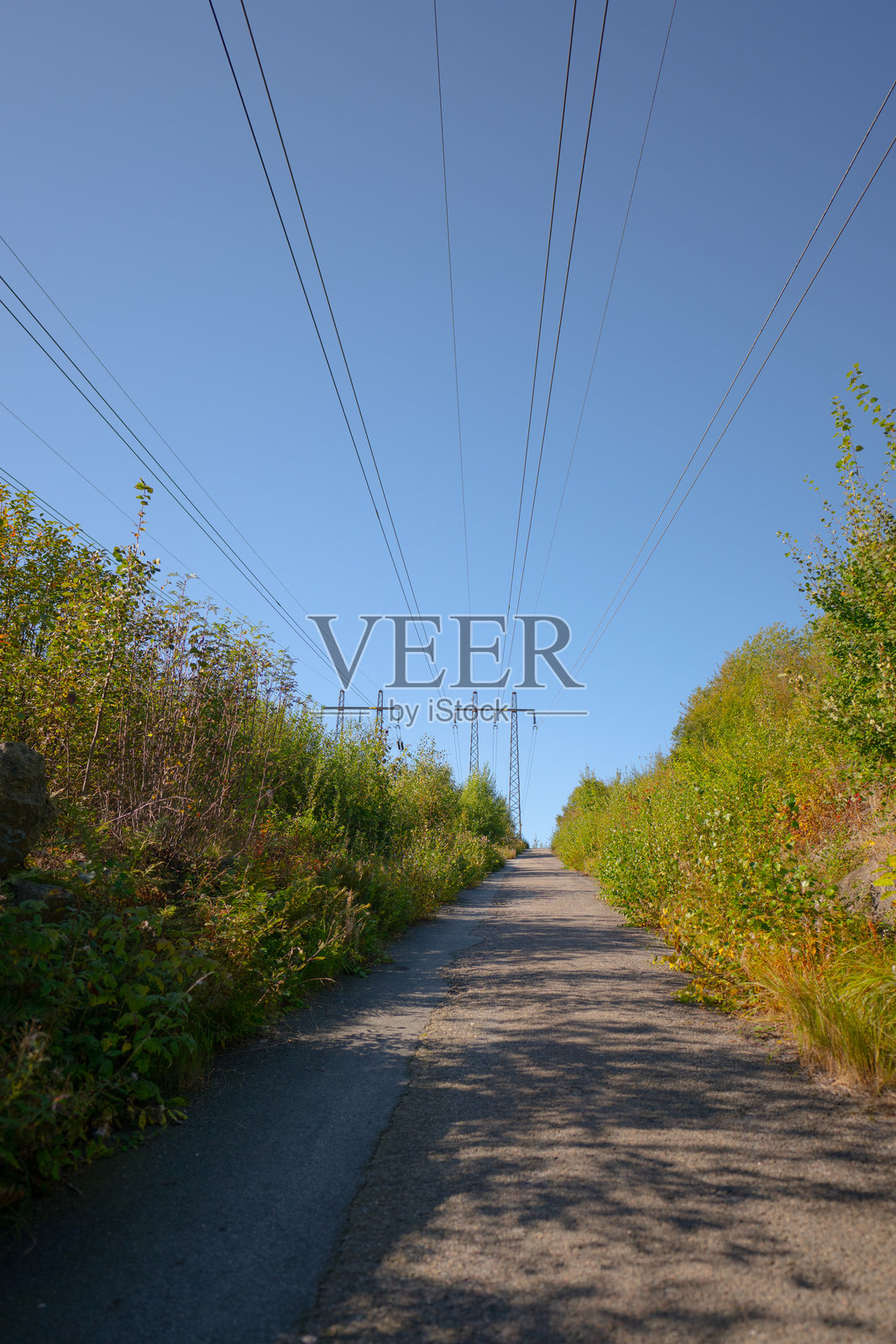 电力线穿过一条狭窄的道路。照片摄影图片