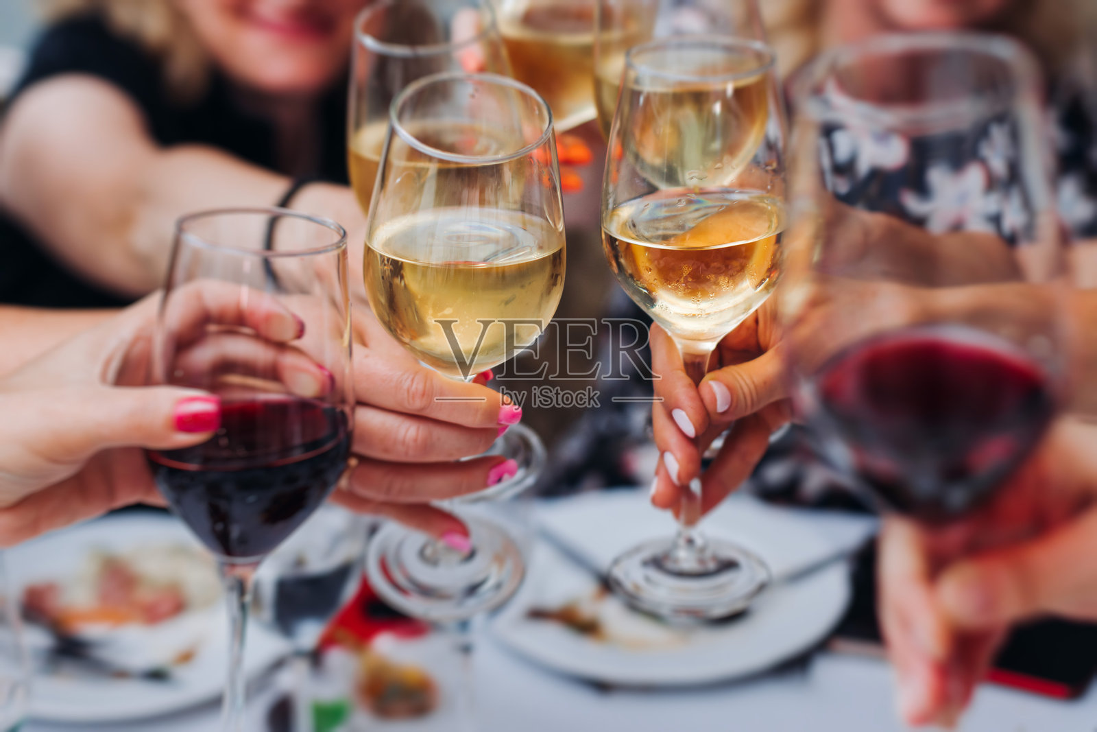 一群客人在餐厅庆祝,举杯祝酒,欢呼着享用葡萄酒和香槟,适用于公司圣诞派对、生日派对、舞会活动或婚礼庆典。照片摄影图片