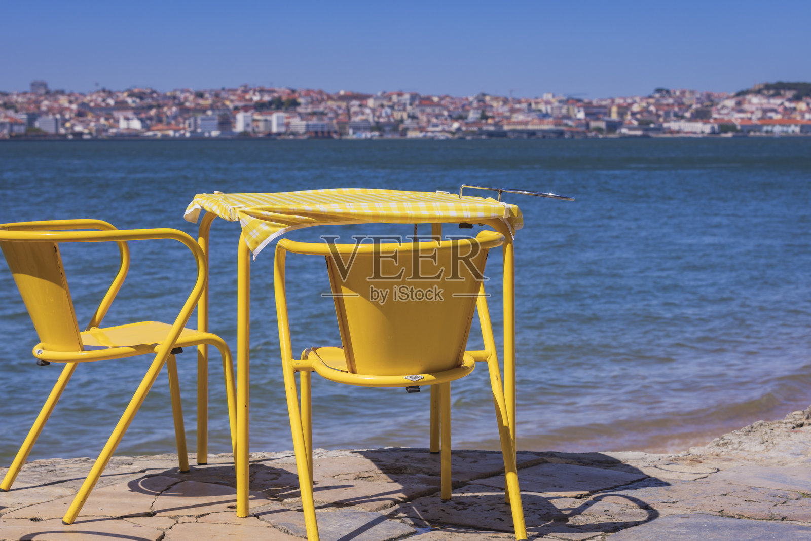 特加斯河沿岸的露台上摆放着椅子和整齐的餐桌,背景是里斯本市中心。照片摄影图片