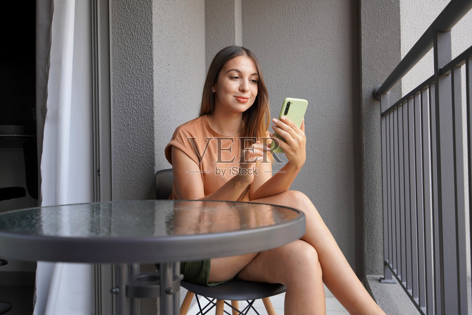 巴西女孩在家阳台上放松,使用智能手机聊天或查看信息照片摄影图片