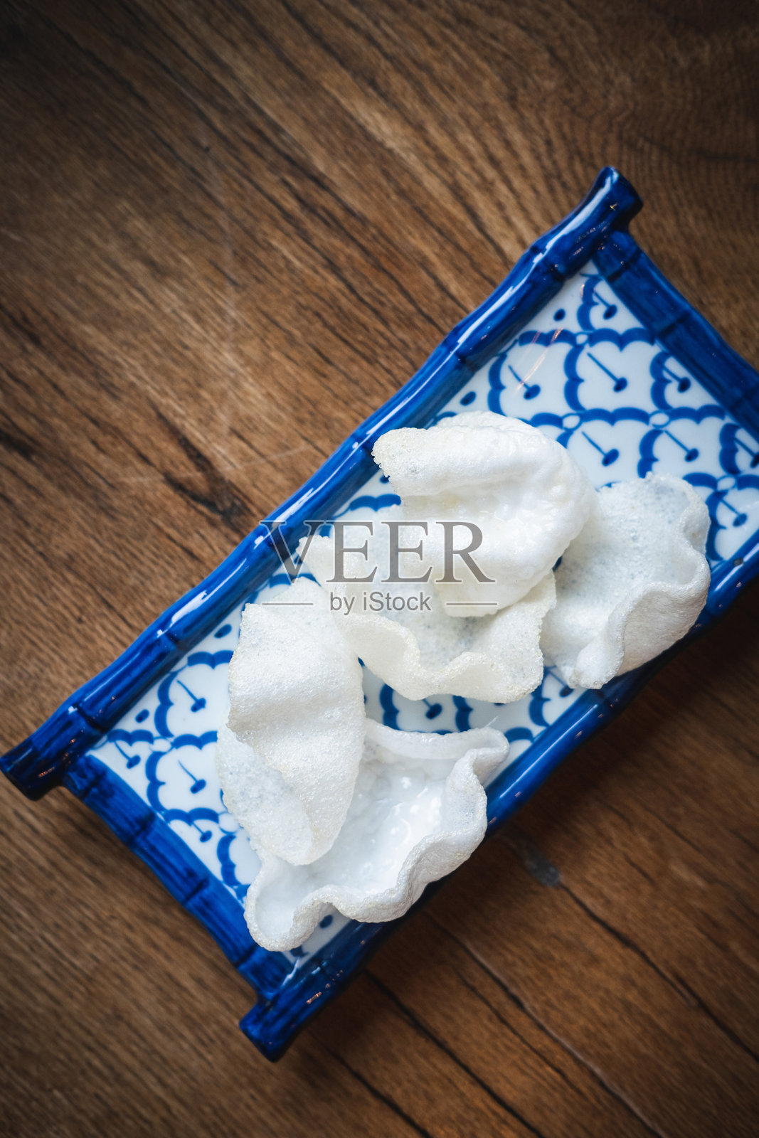 脆皮虾饼盛放在传统的泰式蓝色图案陶瓷盘上,放置在质朴的木桌上,适合餐厅品牌推广和美食摄影的正宗泰国开胃菜。照片摄影图片