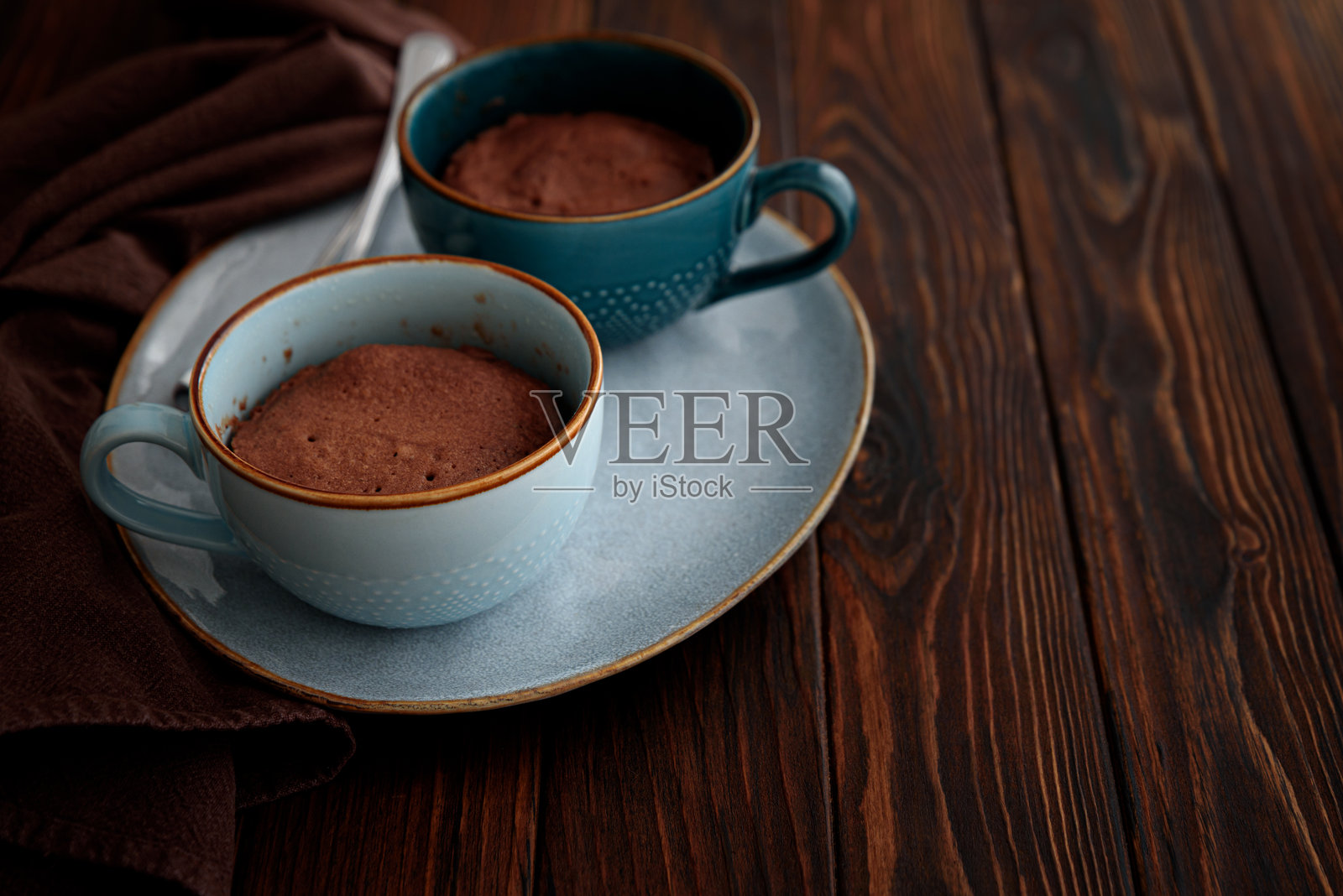 两杯巧克力杯子蛋糕放在深色木桌上。简单的自制甜点。微波炉杯子蛋糕。照片摄影图片