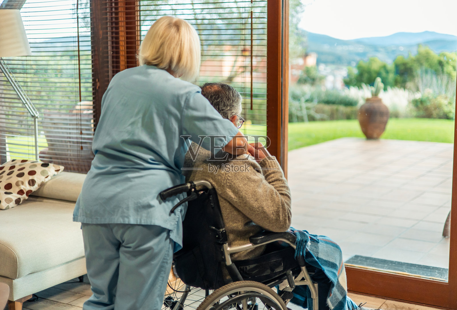 护士安慰坐在轮椅上的老年患者,望着窗外。照片摄影图片