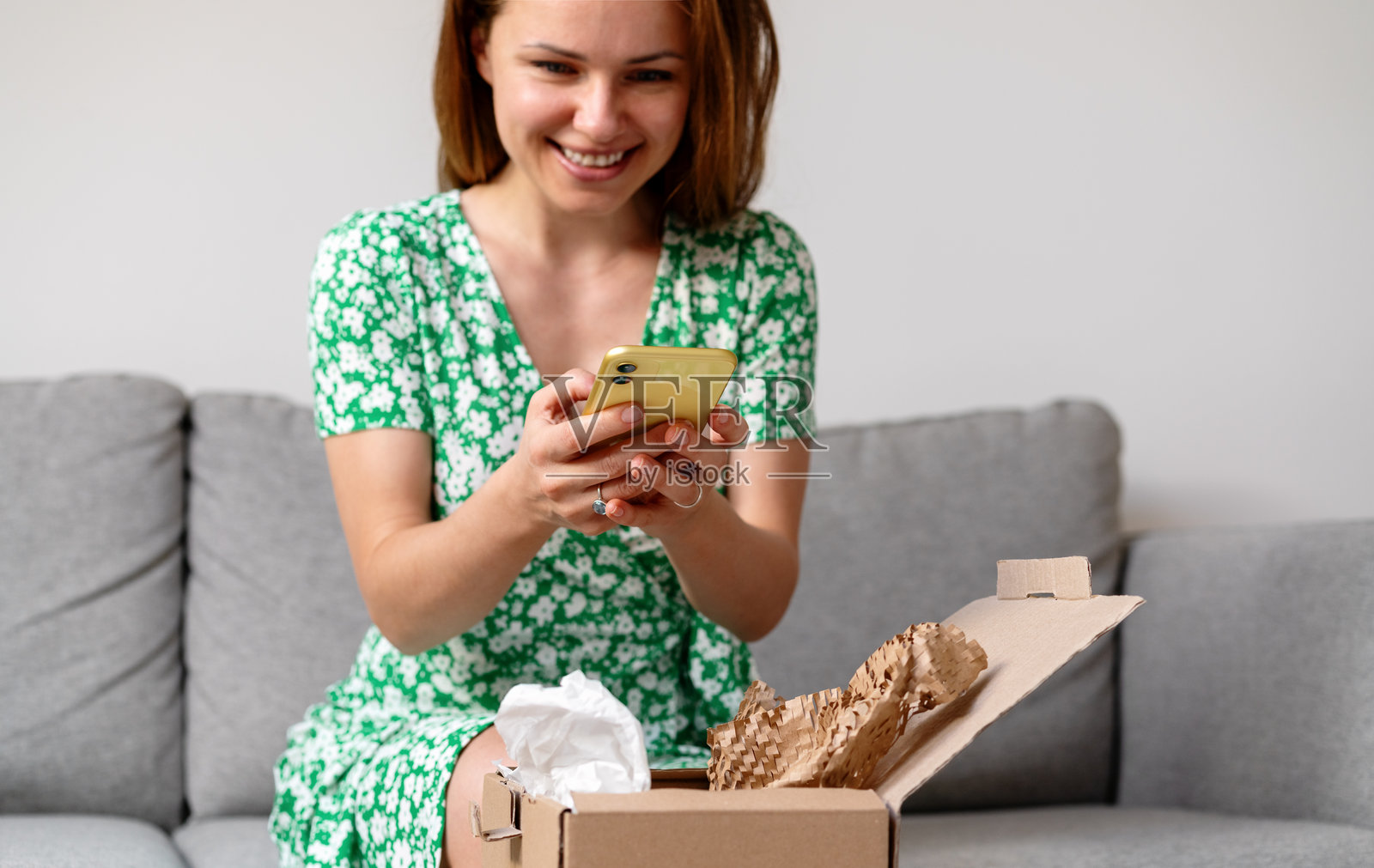 优雅的女性正在拆包快递盒,并拍摄在线购买的商品照片照片摄影图片