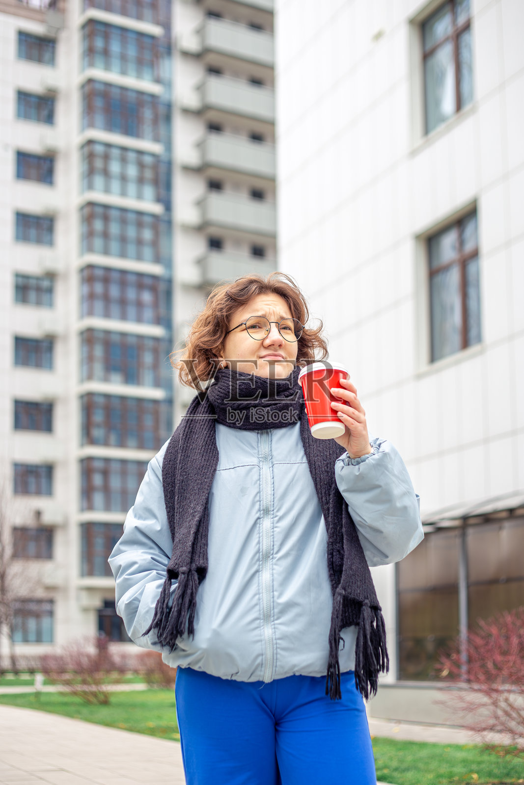 一位年轻女学生手拿咖啡走在城市中。照片摄影图片