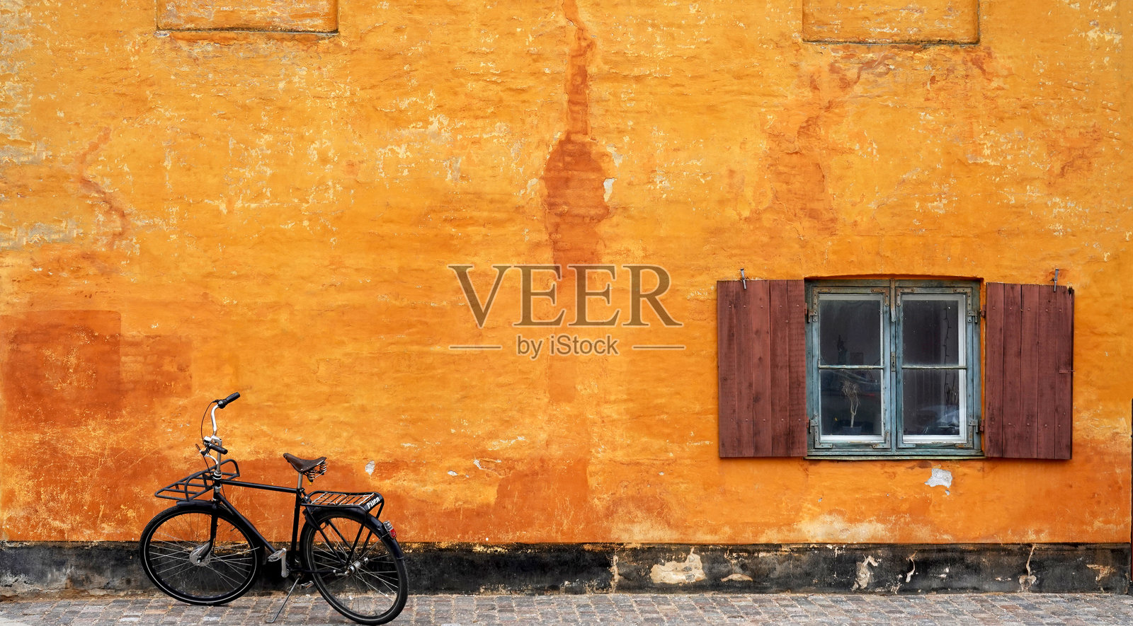 哥本哈根丹麦尼博尔区的旧黄色磨损房屋与自行车。照片摄影图片