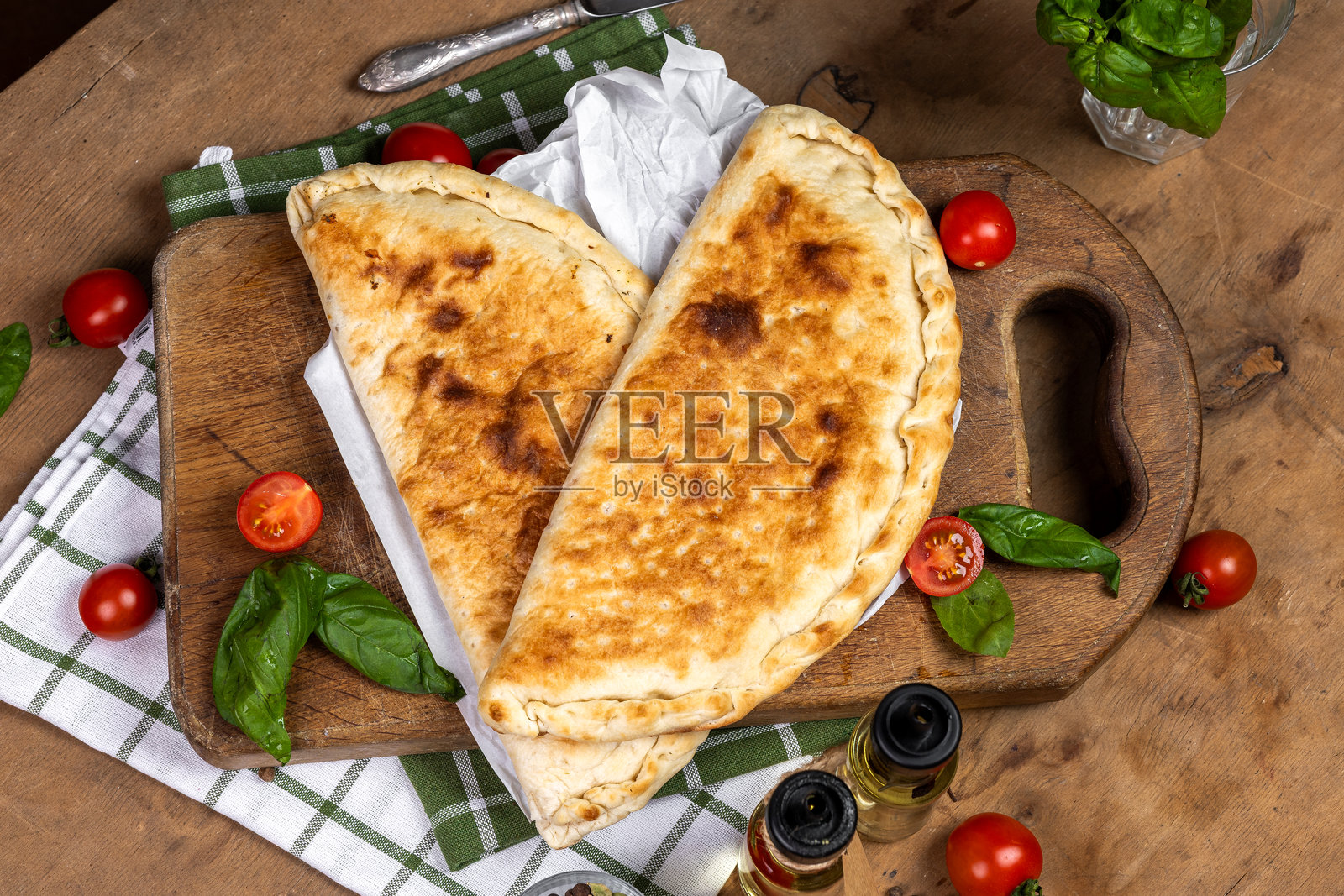 意大利饺子,内含意大利香肠、火腿、奶酪、西红柿、罗勒、蘑菇,搭配奶油酱,背景为木质桌面,意大利糕点,传统意大利美食,橄榄油与香料,食品摄影,俯视图照片摄影图片