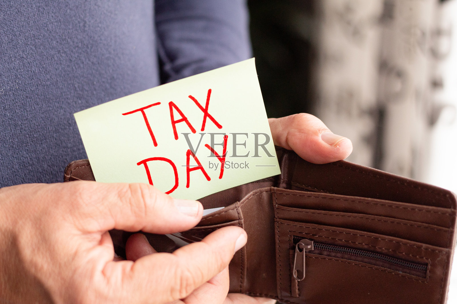 男子从钱包中取出报税日的便条,税务概念。个人财务和税务义务的个人提醒。缴税的重要性。照片摄影图片