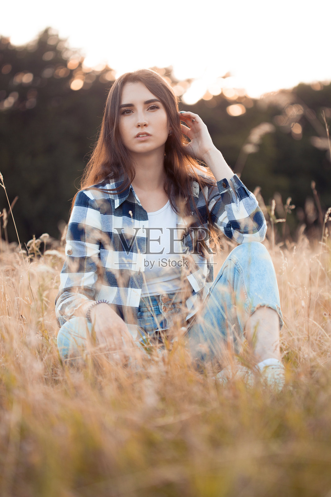 穿着格子衬衫的美丽女性坐在草地上照片摄影图片
