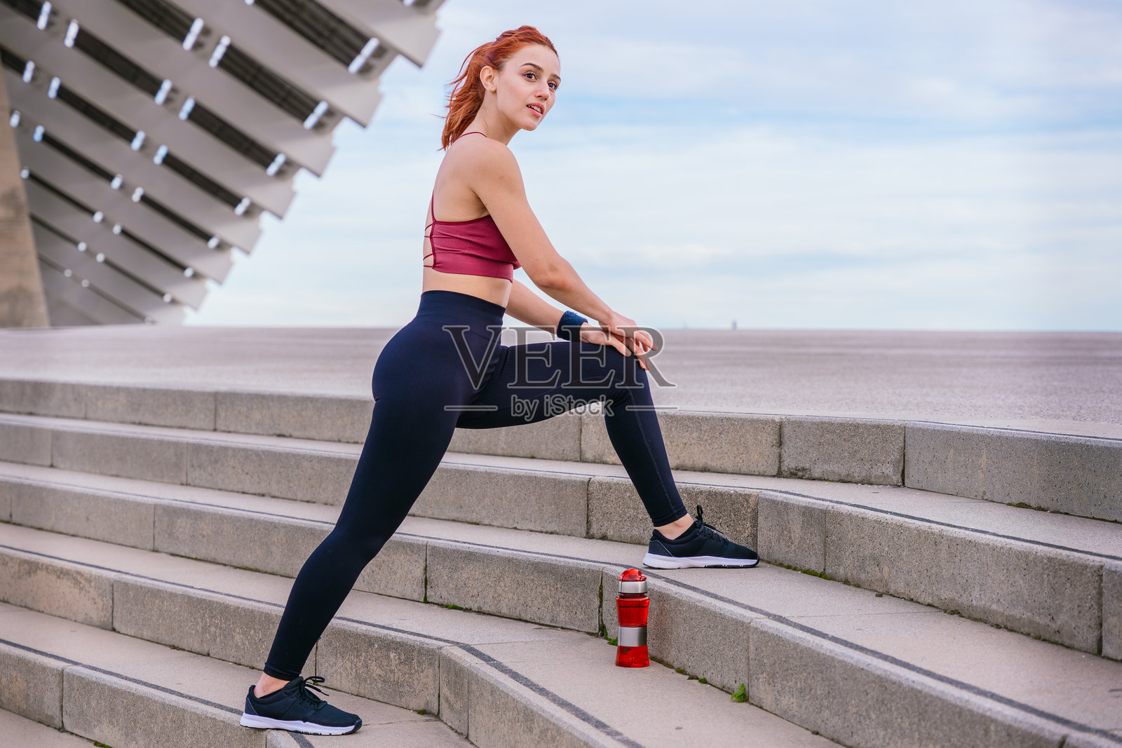 适合的年轻女性在城市环境中的户外楼梯上拉伸照片摄影图片